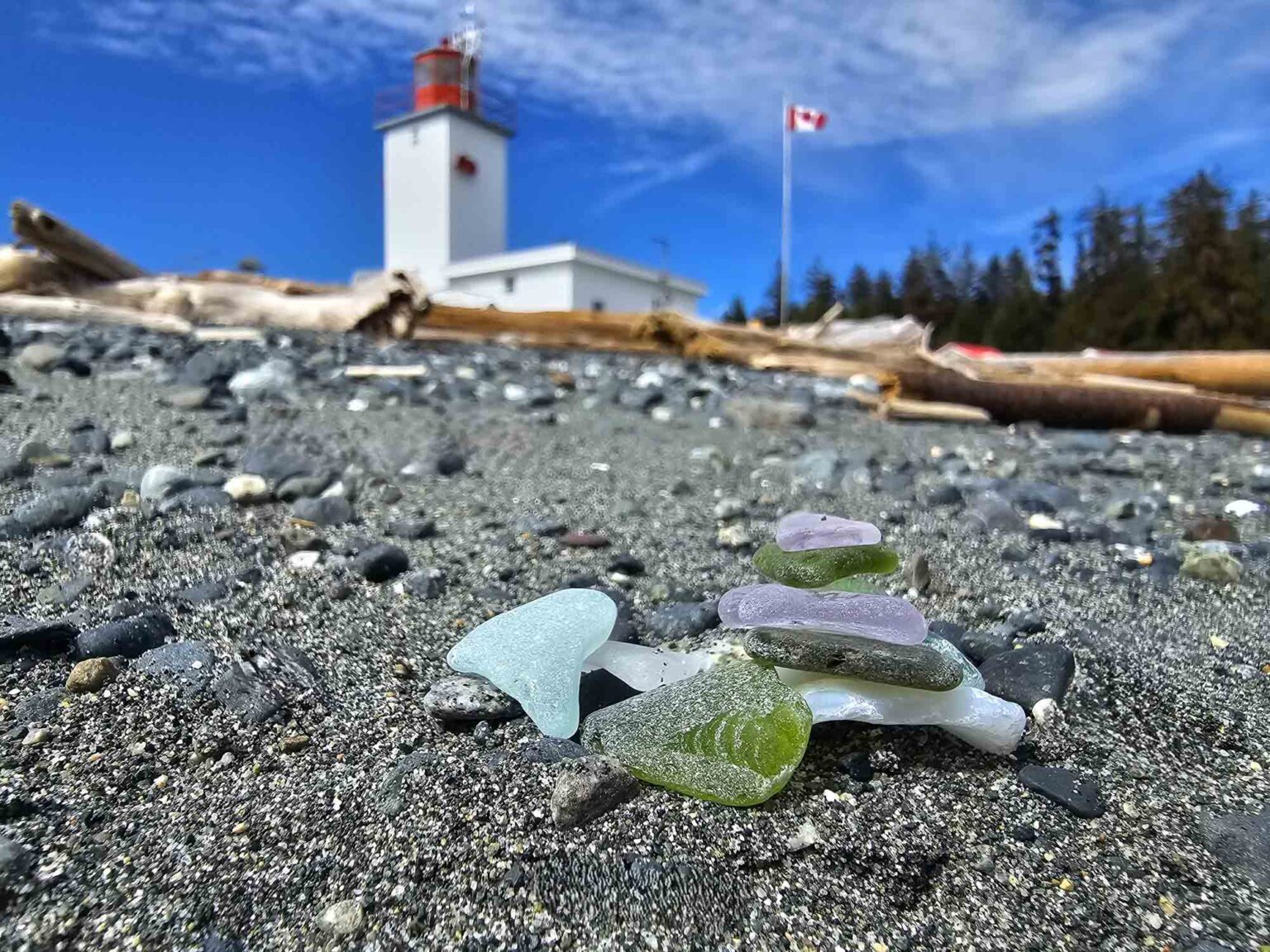 Green and purple Vancouver Island sea glass with a lighthouse and Canadian flag in the background